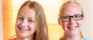 two young girls smiling with braces