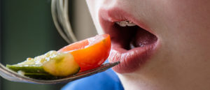 Close-up of a female patient with braces trying to eat vegetables