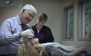 Dr. Rykovich and a female assistant examining a female patient's teeth