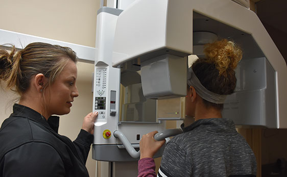 A female staff member taking 3D cone beam scans of a female patient's mouth